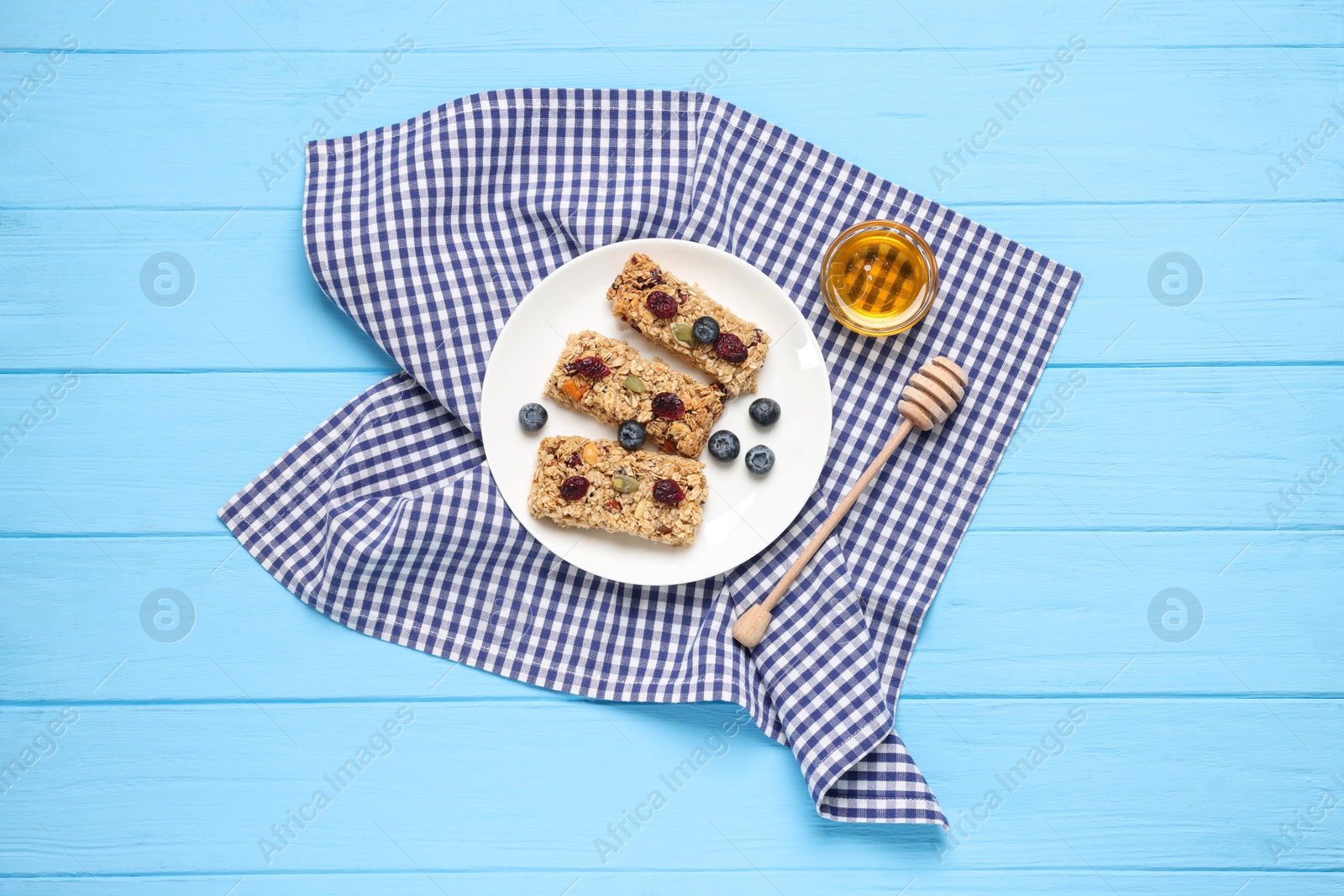 Photo of Tasty granola bars served on light blue wooden table, top view