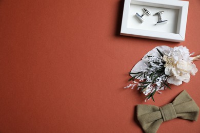 Wedding stuff. Stylish boutonniere, bow tie and cufflinks on brown background, space for text