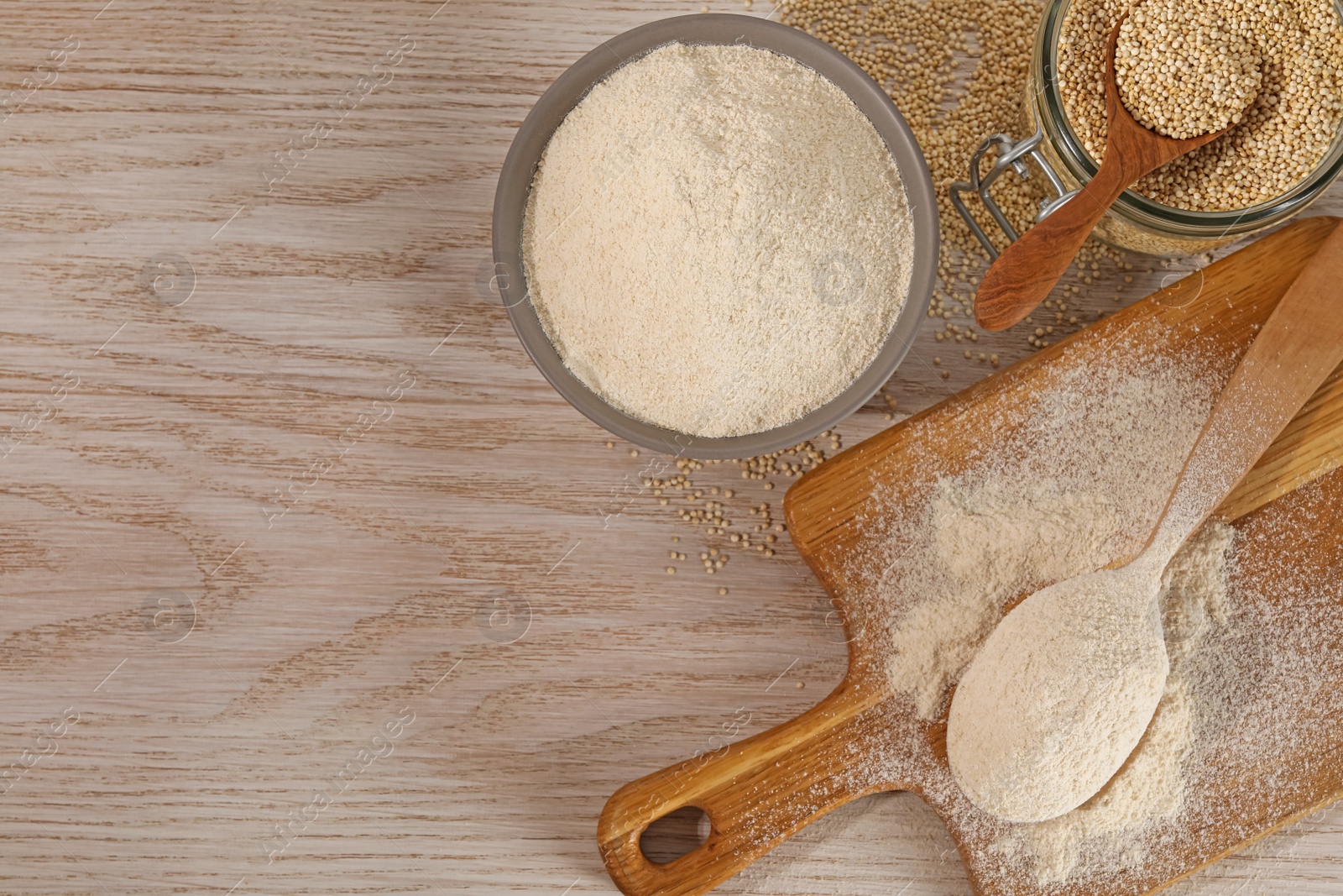 Photo of Spoon and bowl of quinoa flour near jar with seeds on wooden table, flat lay. Space for text