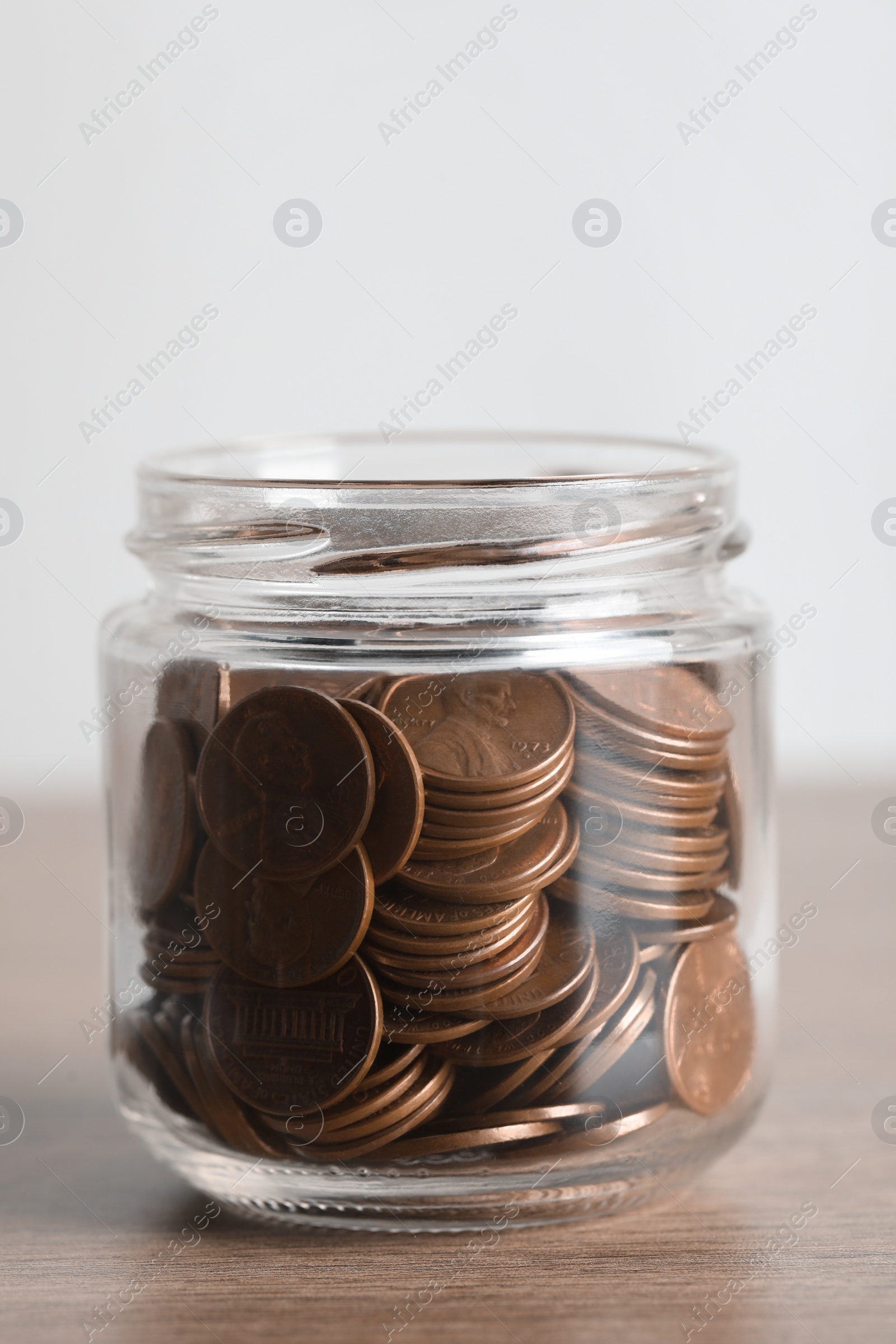 Photo of Glass jar with coins on wooden table, closeup