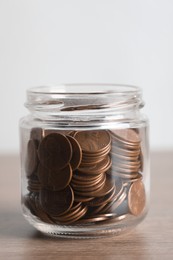 Photo of Glass jar with coins on wooden table, closeup