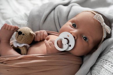 Photo of Adorable newborn baby with pacifier and toy on knitted plaid