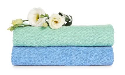 Photo of Folded clean soft towels with flowers isolated on white