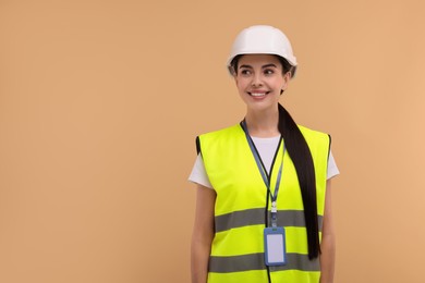 Photo of Engineer with hard hat and badge on beige background, space for text