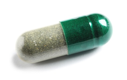 Photo of Green spirulina capsule on white background. Alternative medicine