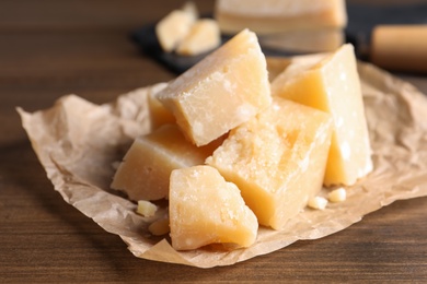 Photo of Pieces of delicious parmesan cheese on wooden table, closeup