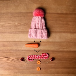 Photo of Funny snowman made with different elements on wooden background, flat lay