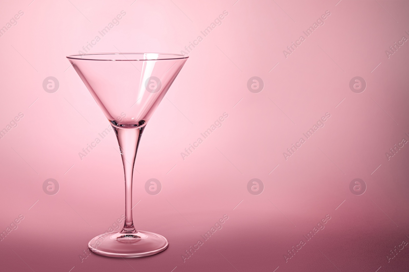 Photo of Elegant empty martini glass on pink background. Space for text