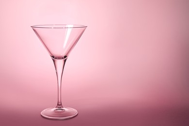 Photo of Elegant empty martini glass on pink background. Space for text