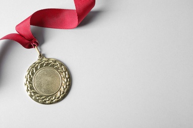 Gold medal with space for design on light background, top view. Victory concept