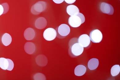 Blurred view of festive lights on red background. Bokeh effect