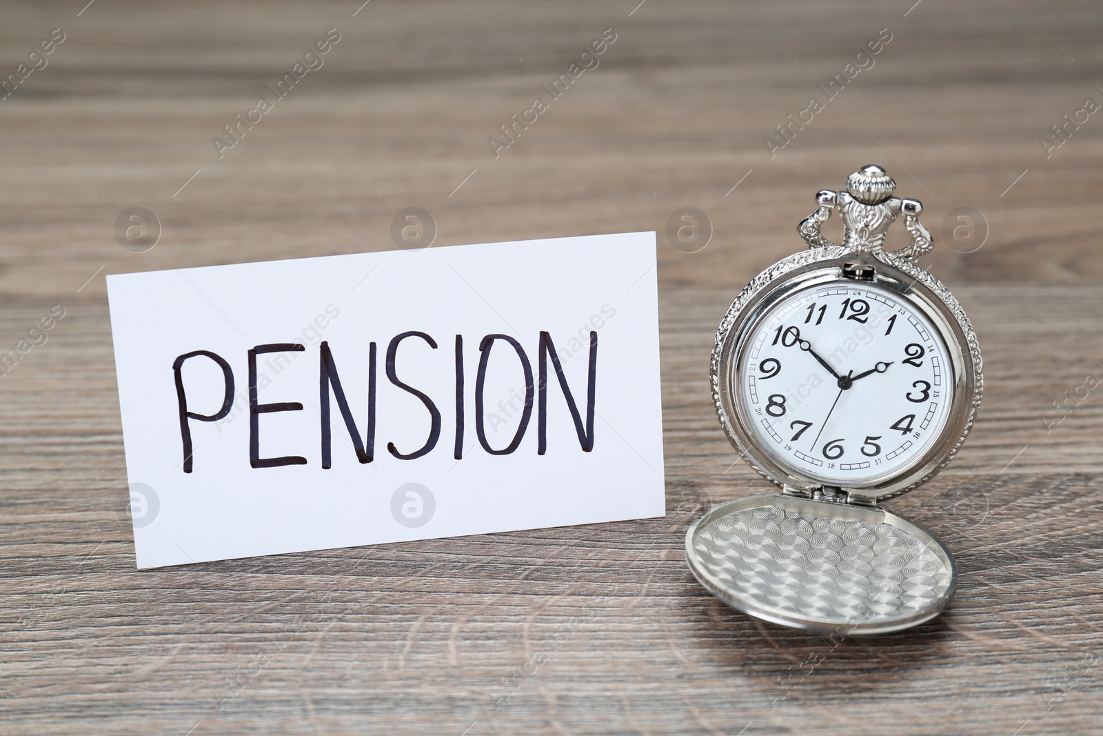 Photo of Card with word Pension and pocket watch on wooden table, closeup