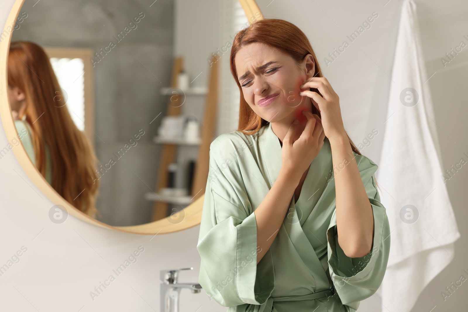 Photo of Suffering from allergy. Young woman scratching her face in bathroom, space for text