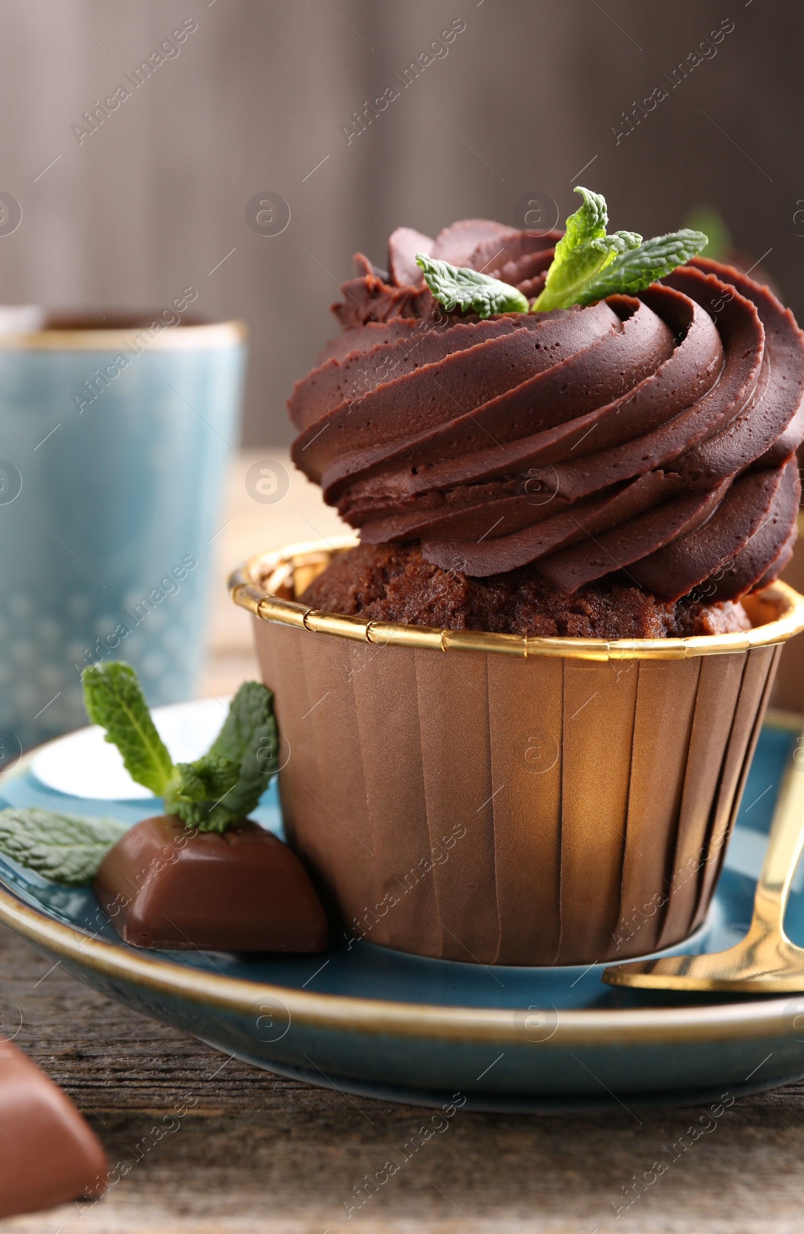Photo of Delicious cupcake with mint and chocolate pieces on wooden table, closeup