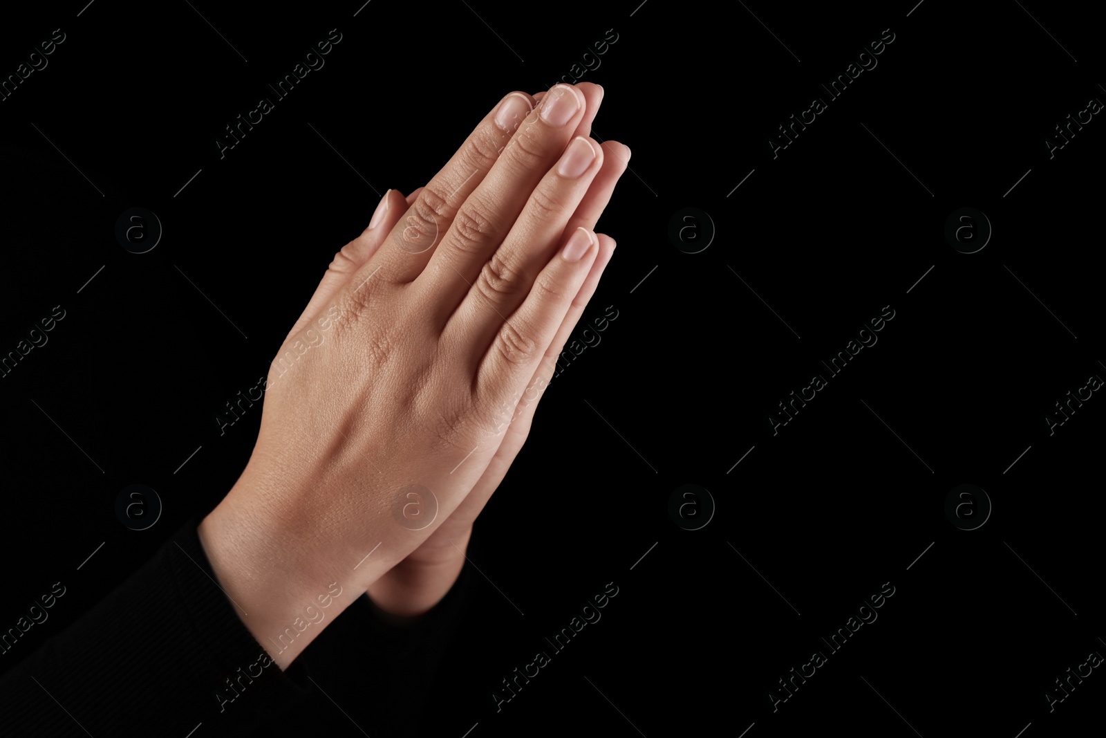 Photo of Woman holding hands clasped while praying in darkness, closeup. Space for text