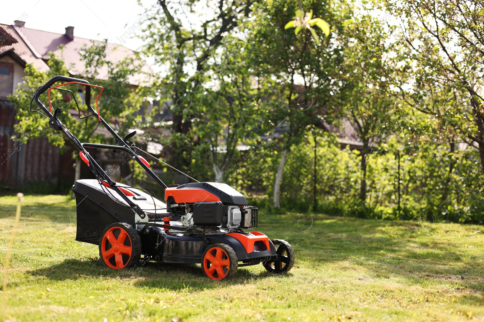 Photo of Modern lawn mower on green grass in garden