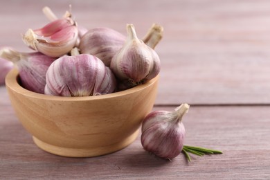 Photo of Bowl with fresh garlic on wooden table, closeup