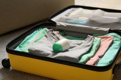 Photo of Deodorant in packed suitcase on floor indoors