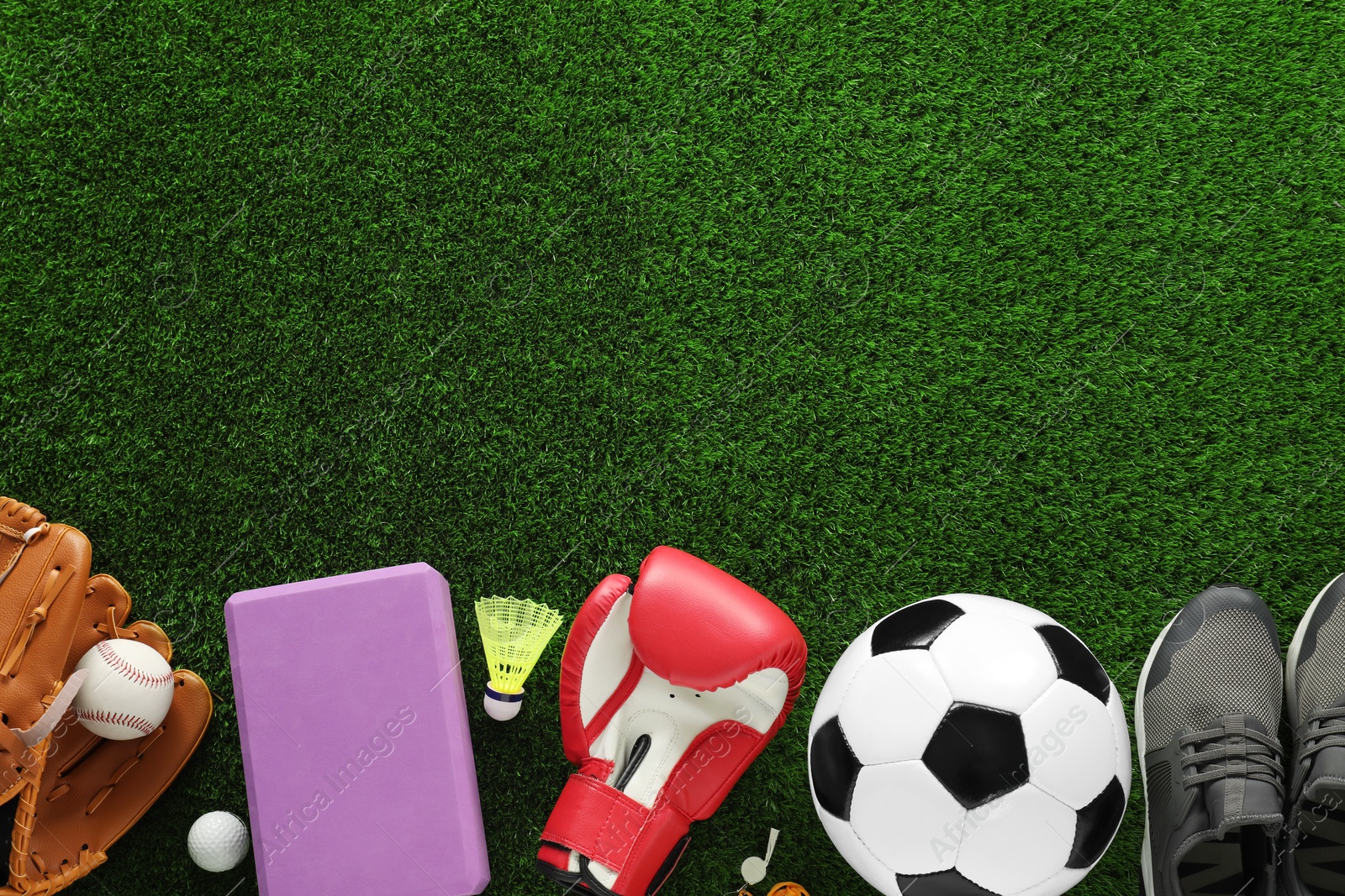 Photo of Different sport equipment and sneakers on green grass, flat lay. Space for text