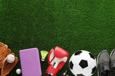 Photo of Different sport equipment and sneakers on green grass, flat lay. Space for text