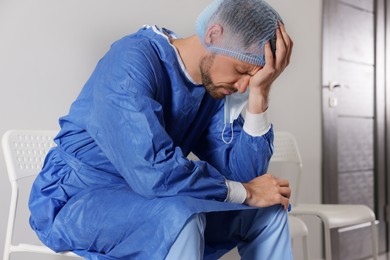 Exhausted doctor sitting on chair in hospital corridor