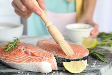 Woman marinating fresh raw salmon at table, closeup. Fish delicacy