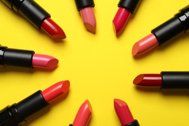 Frame of bright lipsticks on yellow background, flat lay. Space for text