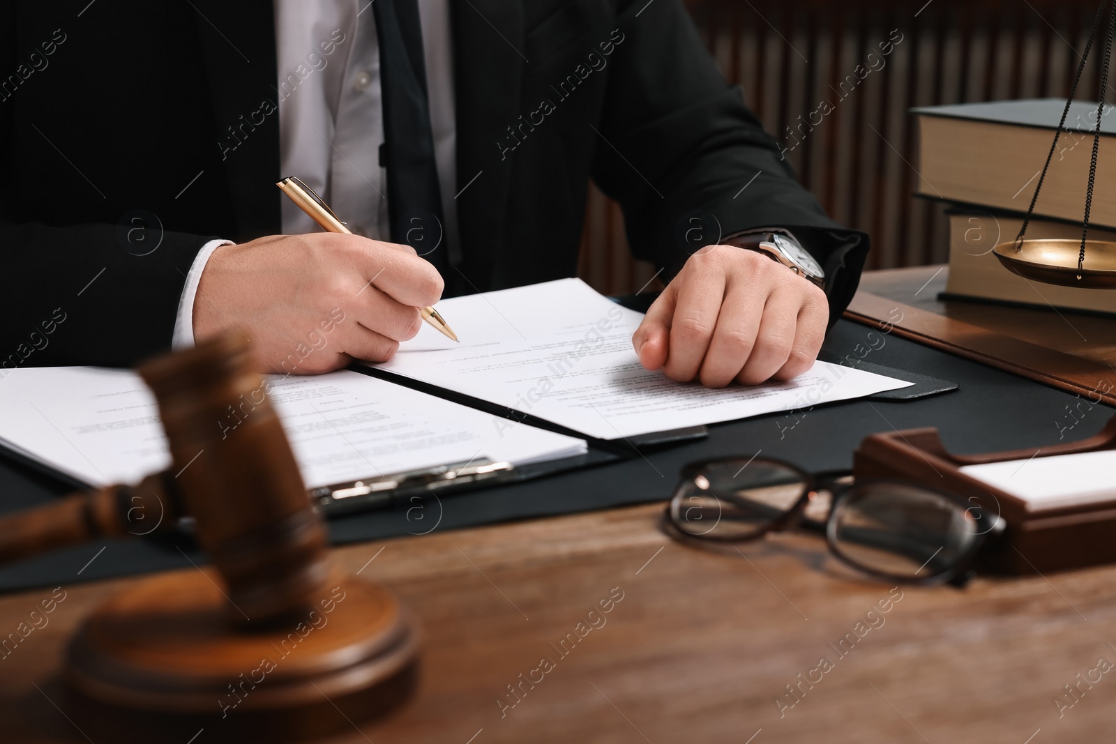 Photo of Lawyer working with documents at wooden table in office, closeup