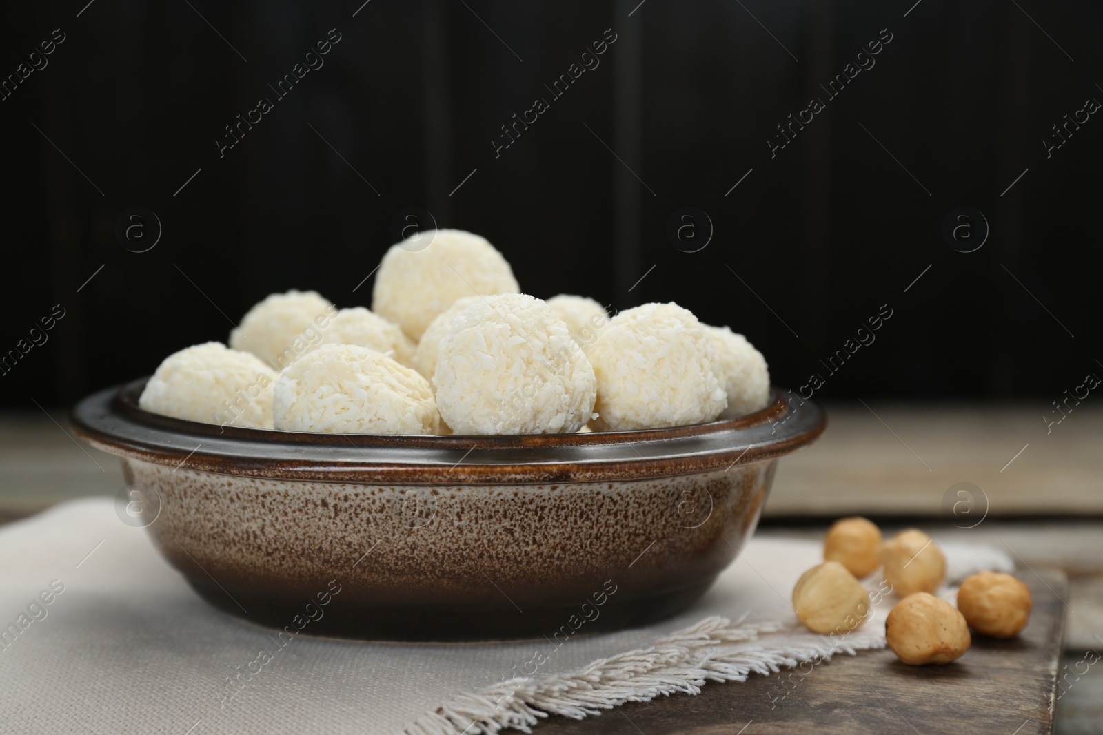 Photo of Delicious candies with coconut flakes and hazelnut on wooden table