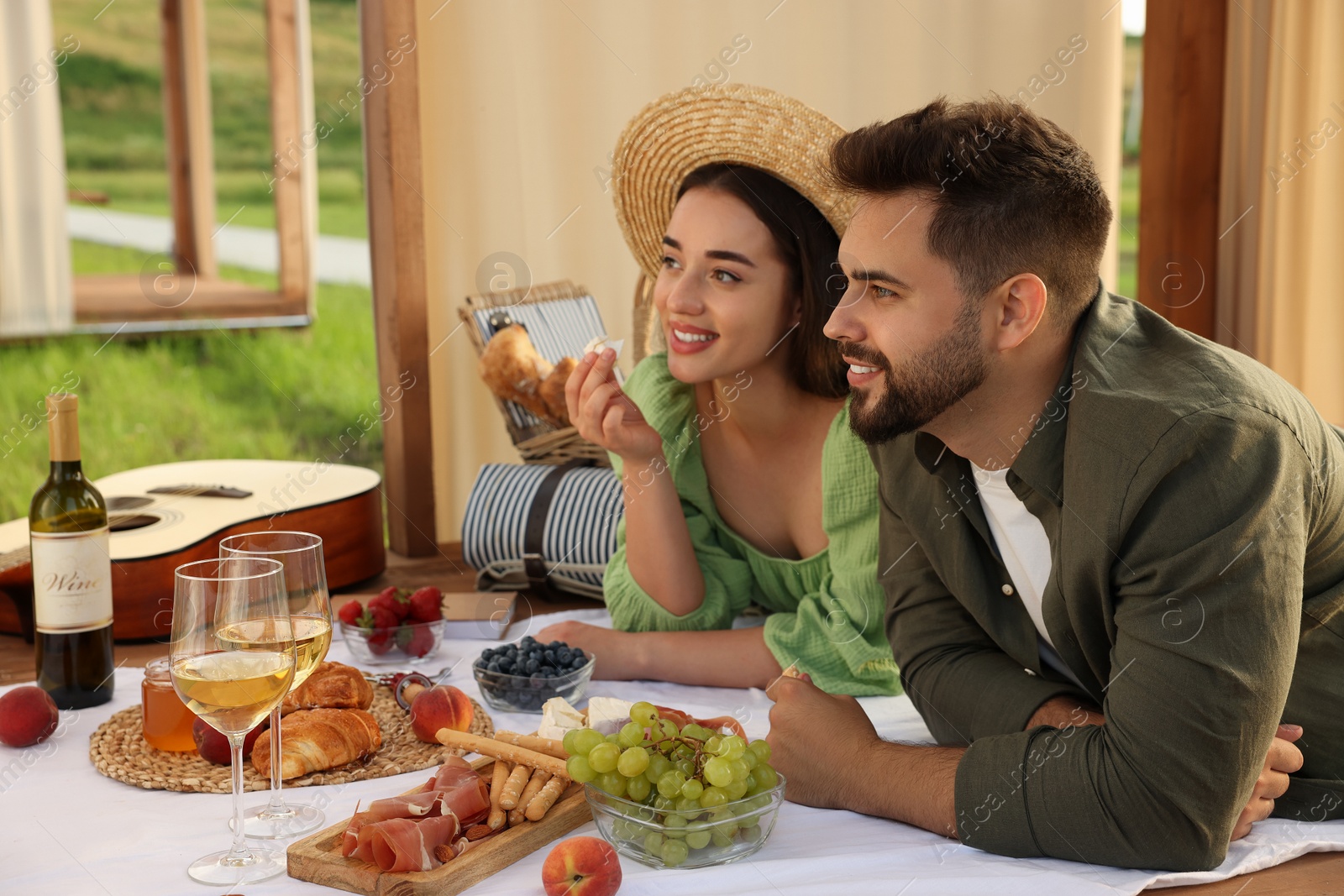 Photo of Romantic date. Beautiful couple having picnic in wooden gazebo