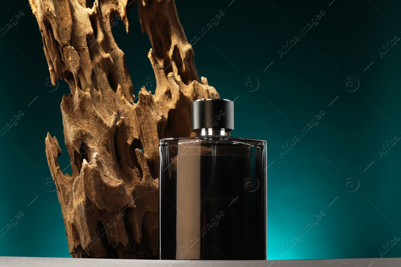 Photo of Luxury men`s perfume in bottle on grey table against color background