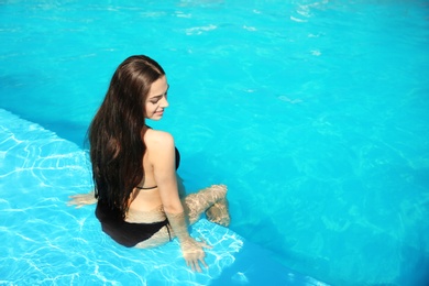 Photo of Beautiful young woman wearing bikini in blue swimming pool