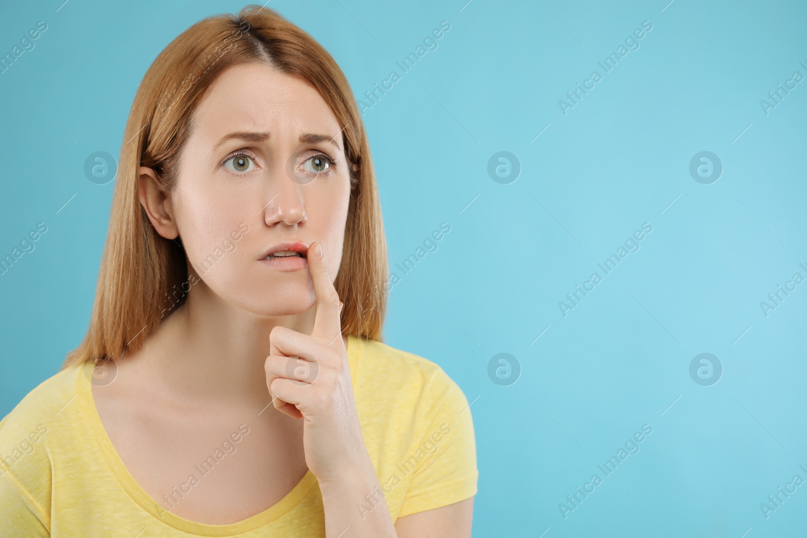 Photo of Upset woman suffering from herpes on light blue background. Space for text