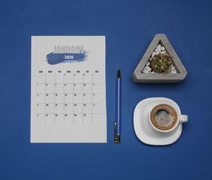 Photo of Flat lay composition with calendar and cup of coffee on blue background