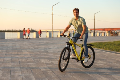 Handsome young man riding bicycle on city waterfront