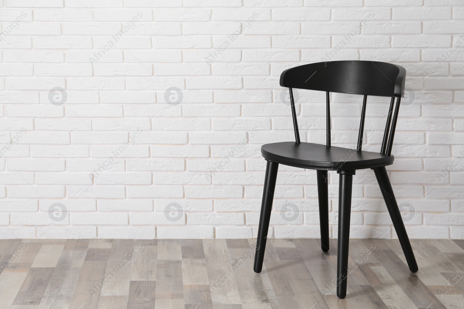 Photo of Stylish comfortable black chair near white brick wall, space for text