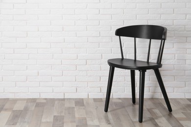 Photo of Stylish comfortable black chair near white brick wall, space for text