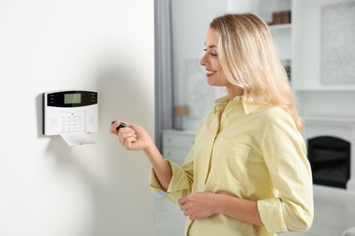 Home security system. Smiling woman using alarm key fob in room