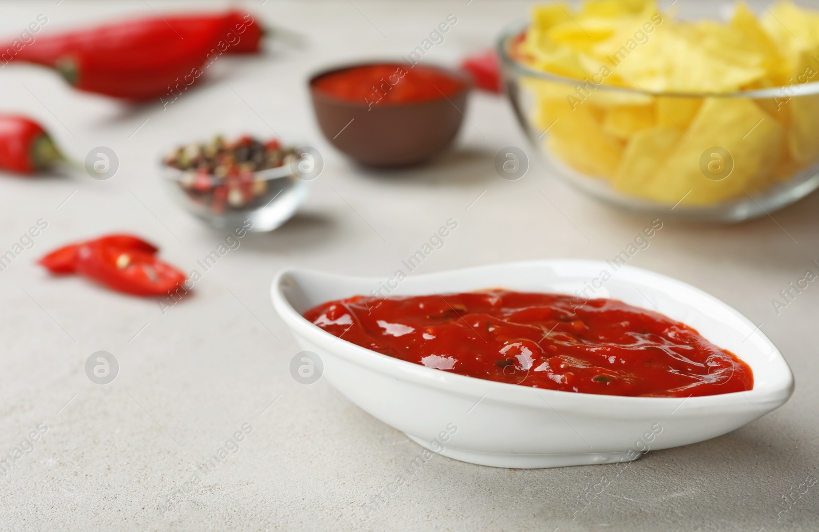 Photo of Gravy boat with spicy chili sauce on light table