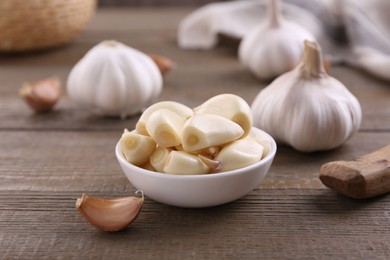 Photo of Aromatic garlic cloves and bulbs on wooden table, closeup