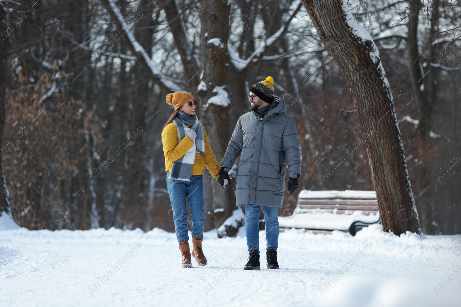 Photo of Happy young couple walking in snowy park on winter day