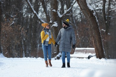 Photo of Happy young couple walking in snowy park on winter day