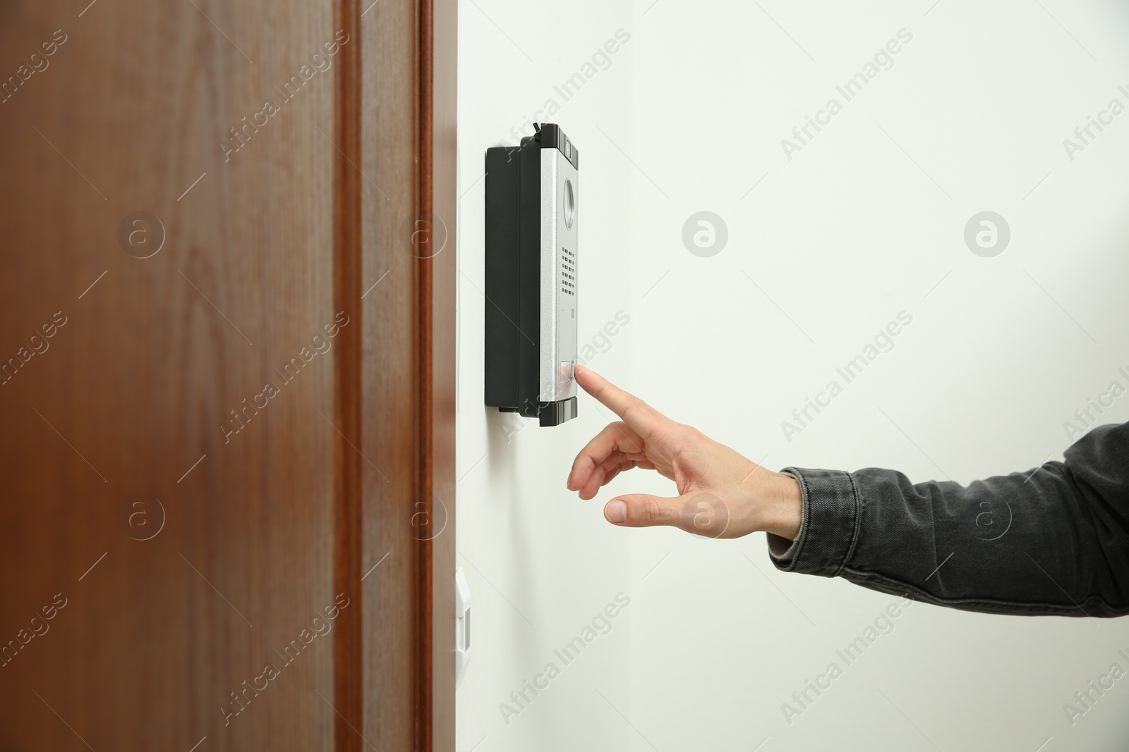 Photo of Man ringing intercom with camera in entryway, closeup