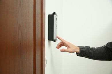 Man ringing intercom with camera in entryway, closeup