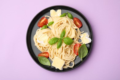 Photo of Delicious pasta with brie cheese, tomatoes and basil leaves on violet background, top view