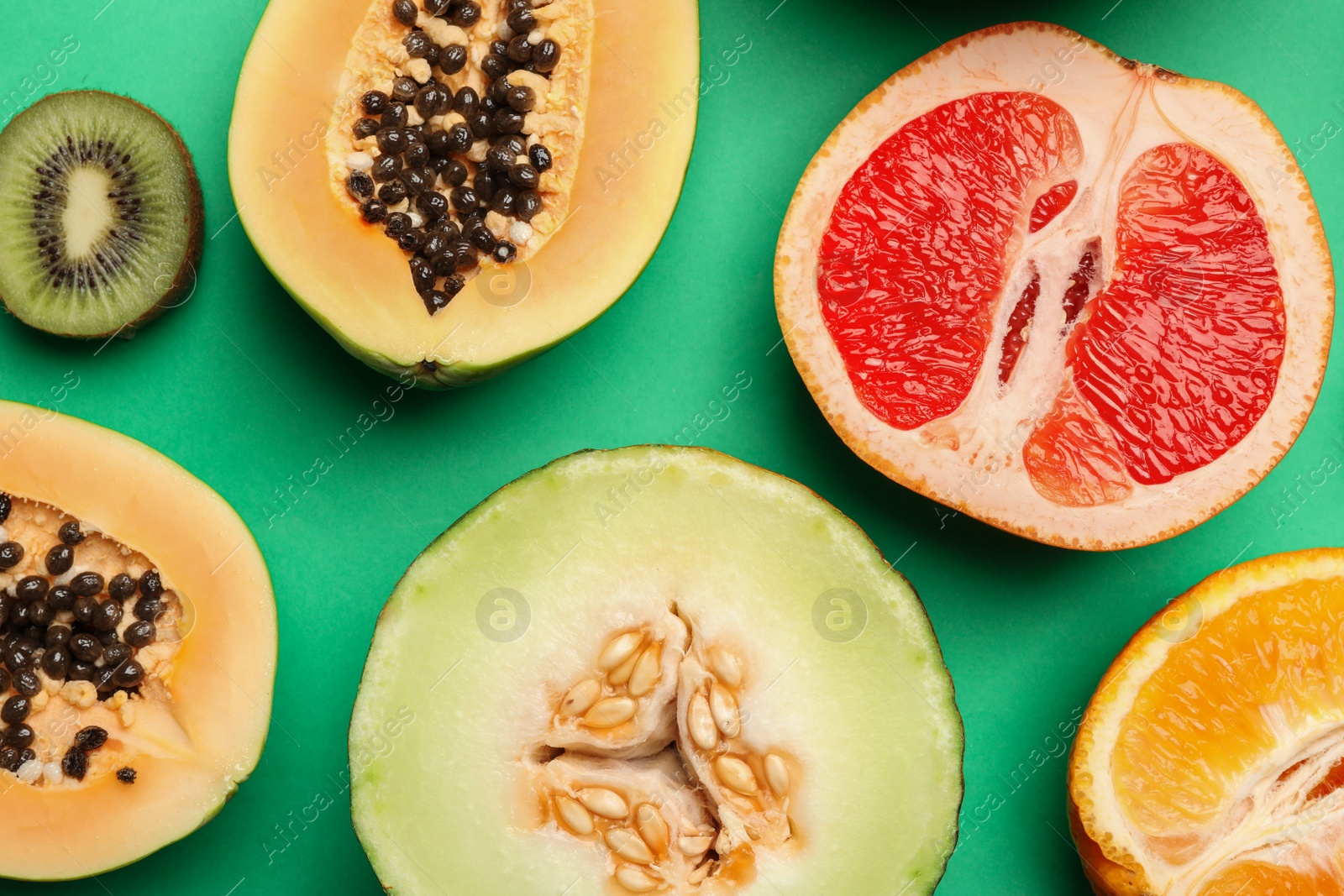 Photo of Flat lay composition with tasty melon and fresh tropical fruits on green background