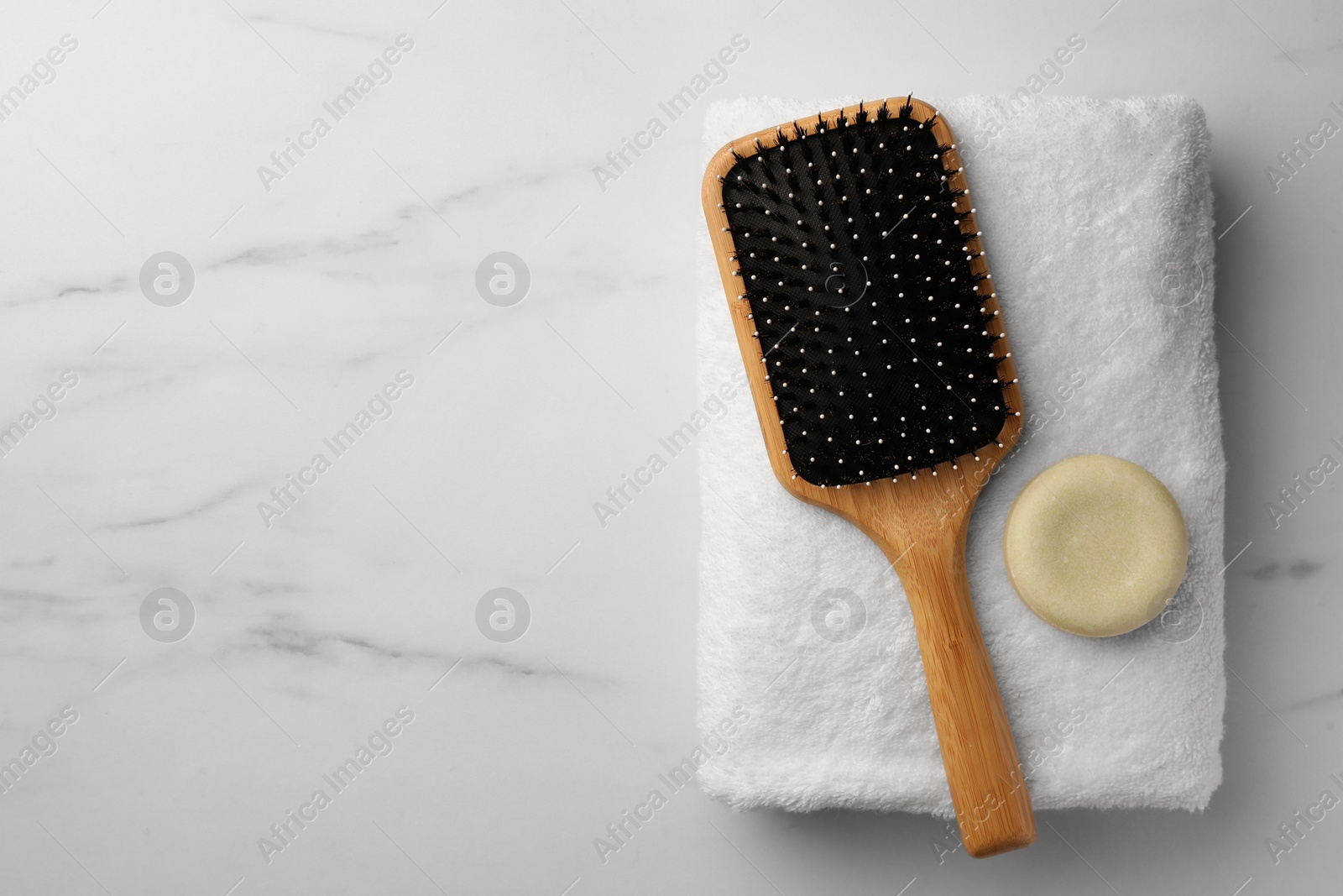 Photo of Wooden hair brush, dry shampoo and terry towel on white marble table, top view. Space for text