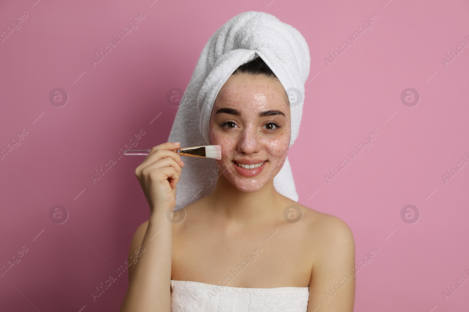 Photo of Woman applying pomegranate face mask on pink background