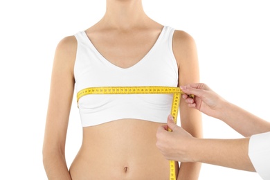 Photo of Doctor measuring size of patient's breast on white background, closeup. Cosmetic surgery