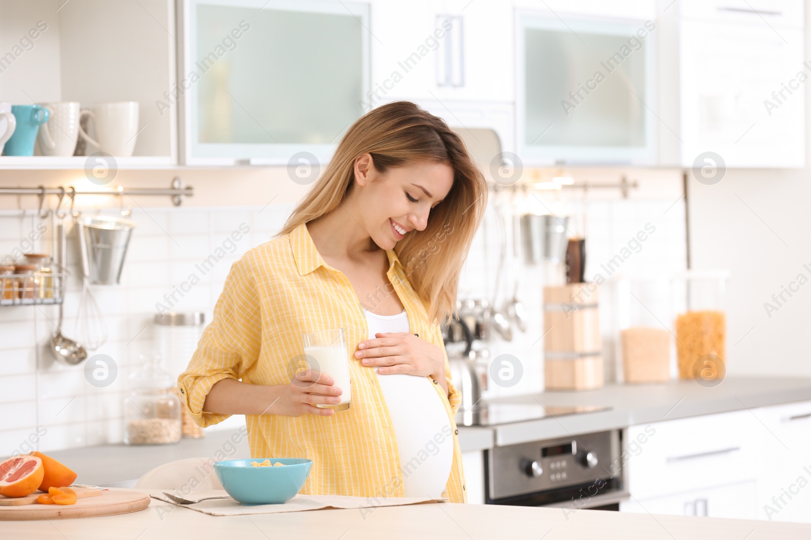 Photo of Beautiful pregnant woman drinking milk in kitchen